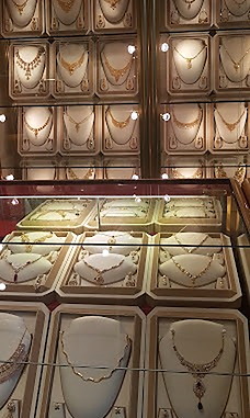 A wall of gold necklace sets illuminated inside the Ramzan Jewellers showroom